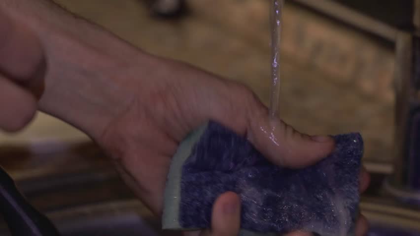 Close Up of Hand Squeezing Sponge with Soap Suds in Sink, Household Cleaning 