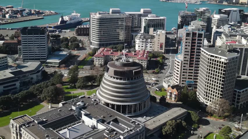 Aerial close up over Beehive with New Zealand flag, Parliament Buildings in Wellington.