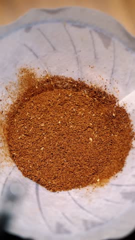 Drip coffee brewing. close-up. barista pours boiling water from a special kettle over freshly ground coffee beans in a paper filter in traditional drip brewing equipment