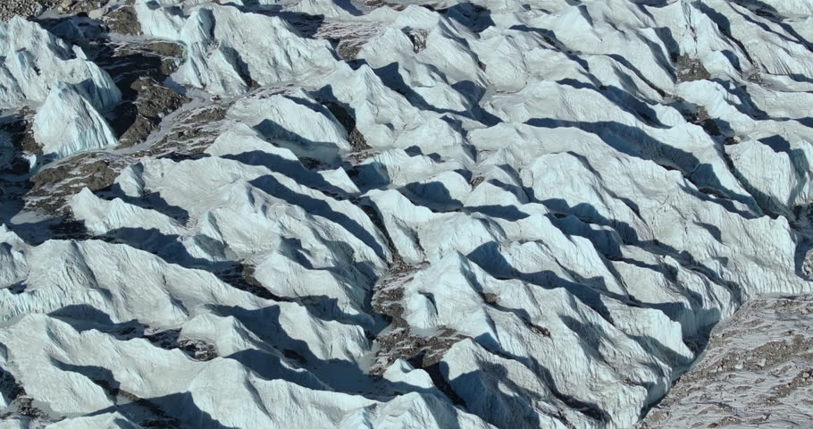 Aerial view of Khumbu Glacier with towering ice formations and glacial meltwater streams beneath the rugged Himalayan peaks in the Everest region of Nepal.