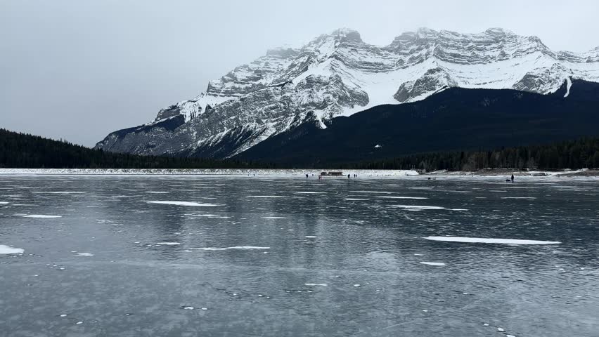 People on a frozen lake skating in the distance, Minewanka, Banff, Alberta, Canada