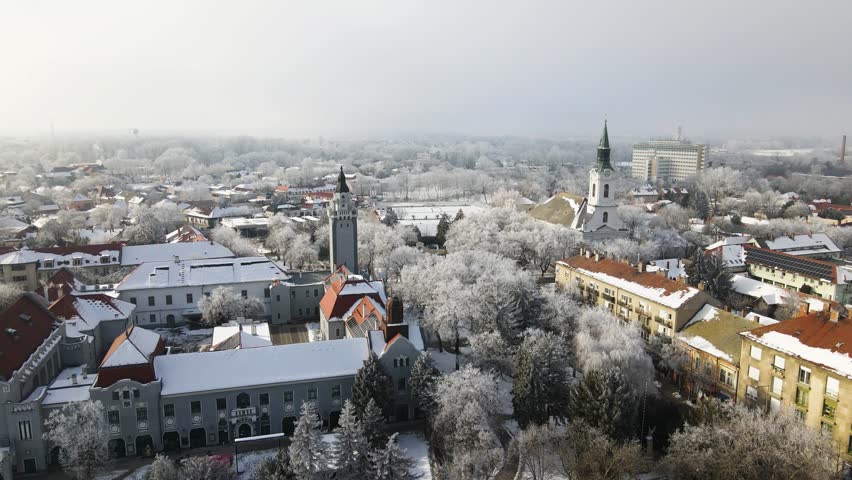 Kiskunhalas city center in Hungary during winter, trees and rooftops covered in snow and hoarfrost with Mayor