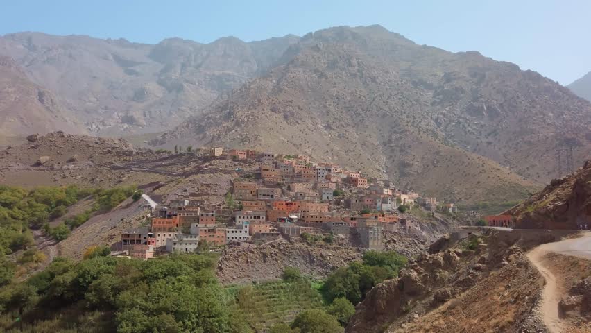 View of Imlil village in Morocco’s High Atlas Mountains, where traditional Berber houses cluster on a rocky hillside above a green valley beneath the rugged slopes of the Mount Toubkal region.