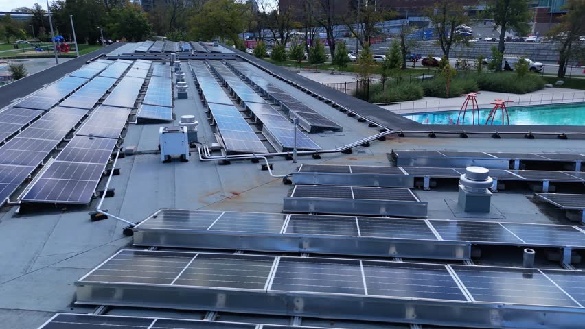 Drone aerial shot: solar panels cover roof of public outdoor swimming pool in Halifax. Renewable energy production in urban setting, Nova Scotia Canada, bright daylight view 4K.