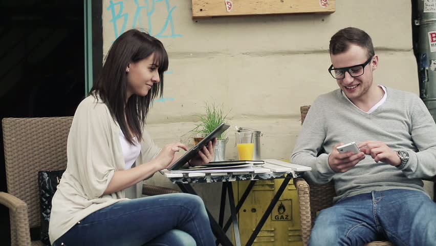 Happy couple with smartphone and tablet in cafe, steadicam shot