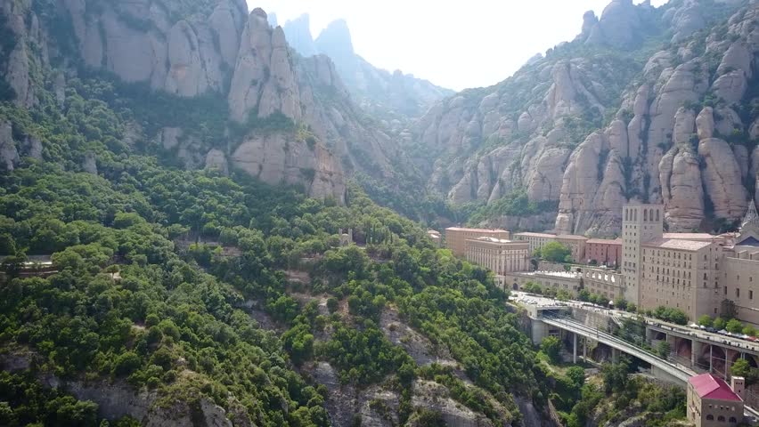 Drone footage of an epic mountain settlement called Montserrat in the foothills of Spain close to the city of Barcelona. There is a monastery that sits at the top of the road system.