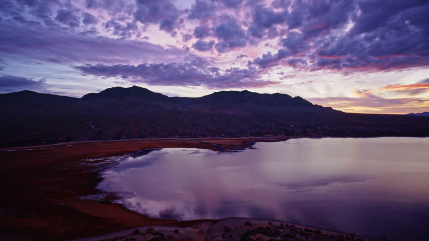 Sweeping drone shot of colorful sunrise lighting Caballo Lake State Park in New Mexico.