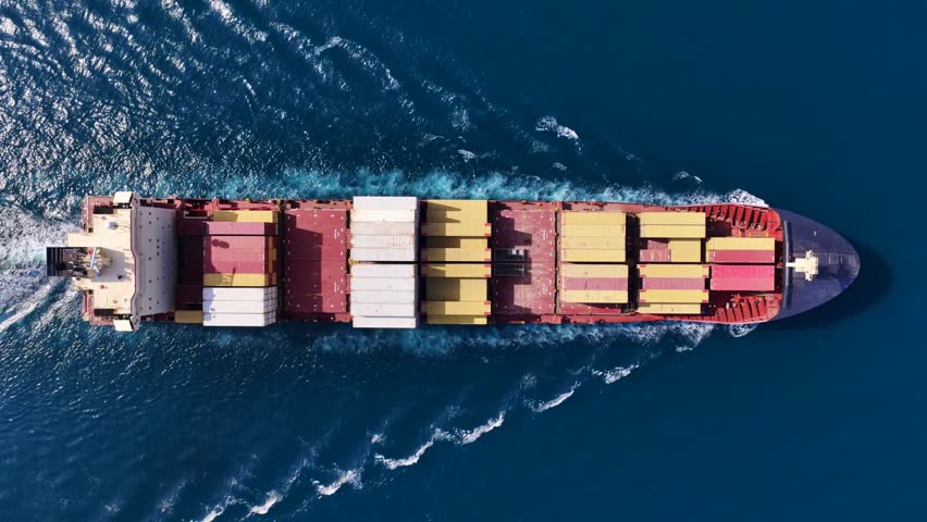 Aerial drone too down cinematic tracking loop video of container ship cruising deep blue open ocean sea