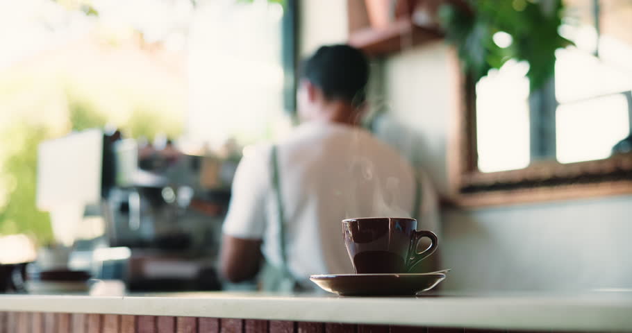 Coffee, cup and counter in cafe with steam, small business worker and barista for customer service. Mug, morning beverage and espresso on table with man, drink order preparation and waiter at store.