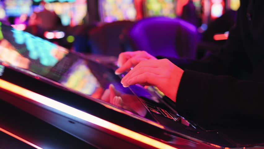 A man is playing slots machine and roulette or poker, gambling in casino close up, game machine in cafe or hotel lobby. Playing betting game.