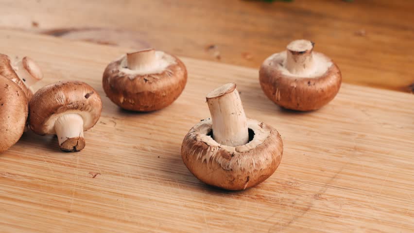 Freshly picked mushrooms on home kitchen, close up texture of brown Champignon, woman cooking tasty vegan dinner. 