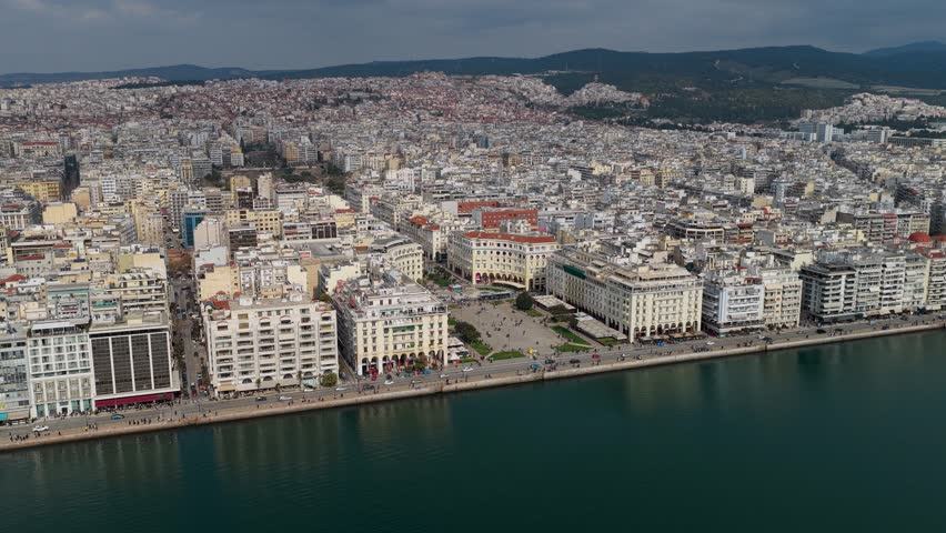 Aerial footage of Aristotelous Square in Thessaloniki, showing the waterfront, neoclassical buildings, pedestrian areas and the dense urban landscape of the city.