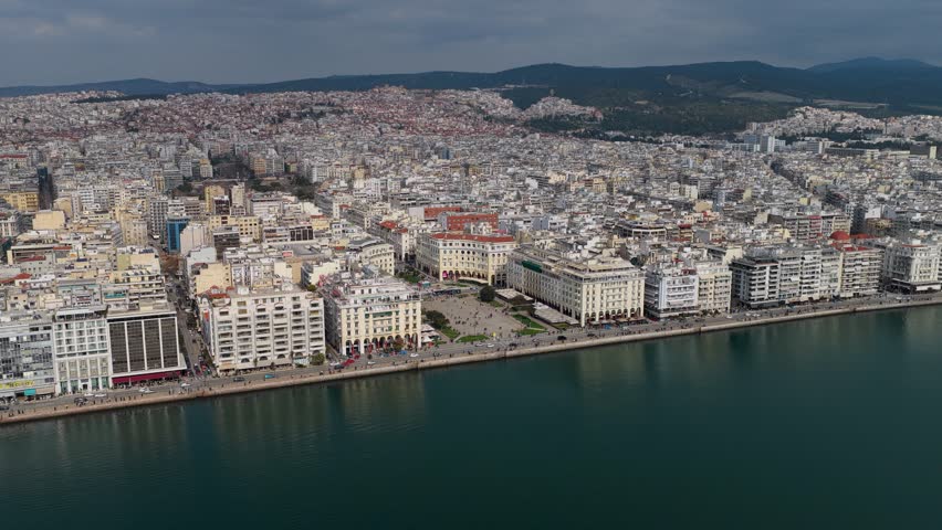 Aerial footage of Aristotelous Square in Thessaloniki, showing the waterfront, neoclassical buildings, pedestrian areas and the dense urban landscape of the city.