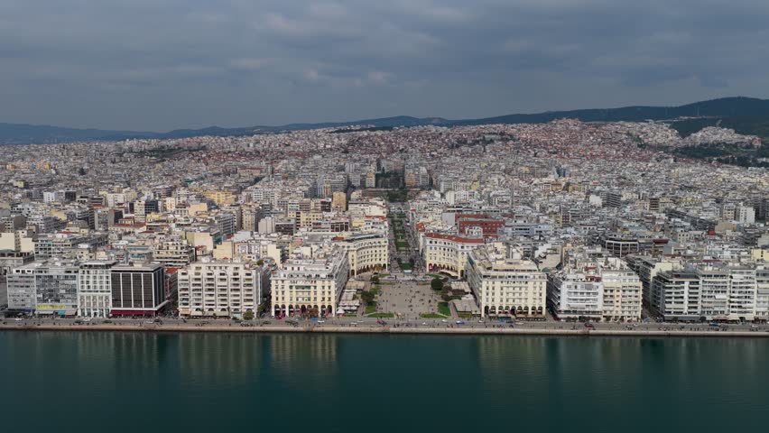 Aerial footage of Aristotelous Square in Thessaloniki, showing the waterfront, neoclassical buildings, pedestrian areas and the dense urban landscape of the city.