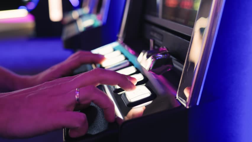 A man is playing slots machine and roulette or poker, gambling in casino close up, game machine in cafe or hotel lobby. Playing betting game.