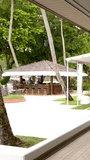 A slow panning shot reveals an empty upscale outdoor dining area at a tropical resort - Powered by Shutterstock - Get 15% off with code: PIKWIZARD15