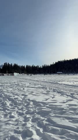 Banff, Canada - February 2, 2026: People walking on lake Louise against beautiful mountains, camera moving right