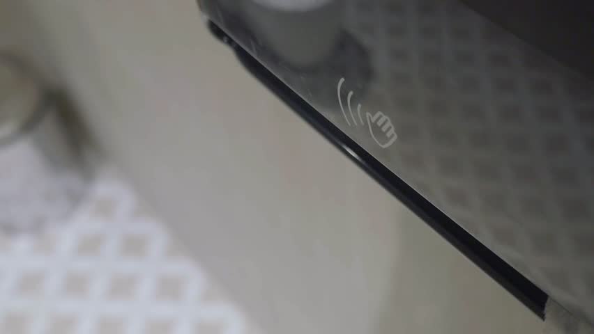 Close up video of person pulling and tearing white paper towel from dispenser with hand in public restroom