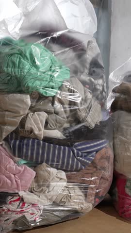 Piled bales of used childrens clothes and shoes representing global textile waste problem and overconsumption