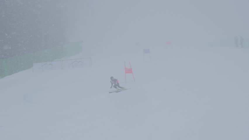 Skier Making Sharp Turn. Skier Executing Precise Turn Through Snowy Slalom Course With Determination. Focused Athlete Skillfully Carving Sharp Turns On Powdery Slopes With Safety Barriers Around