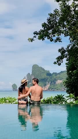 Couple enjoys a serene moment in an infinity pool, surrounded by lush greenery and breathtaking ocean views in Koh Phi Phi, Thailand. Perfect for dream vacations and romantic getaways.