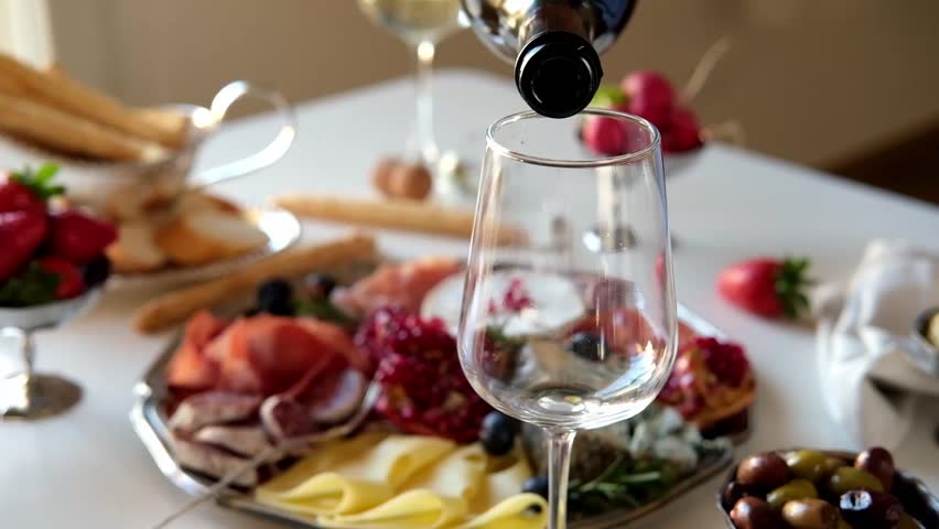 Pouring white wine or Prosecco into a glass from a bottle for an aperitif