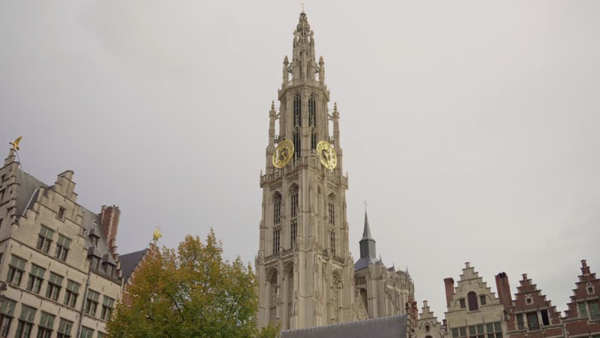 Cathedral of Our Lady Antwerp with golden clock on the tower against cloudy sky, Belgium. Gothic architecture of the historic landmark in autumn.
