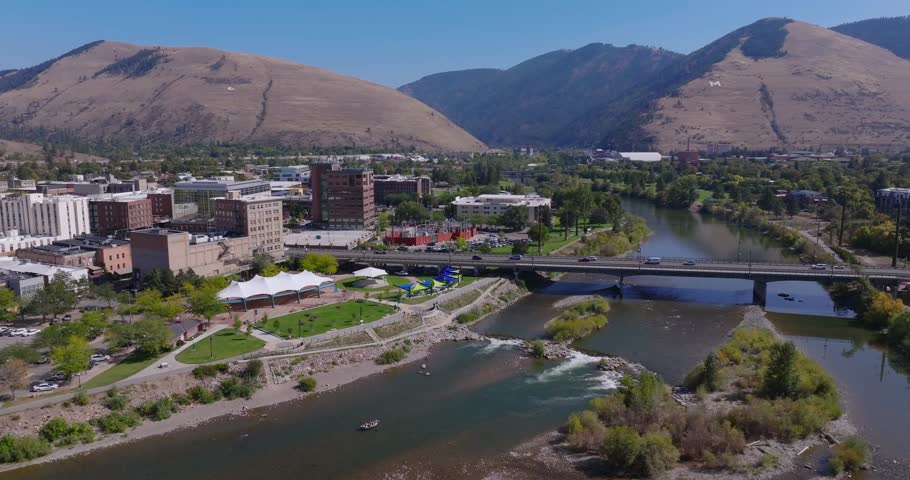 Wide aerial orbit of Missoula Montana riverfront and city blocks, Clark Fork River