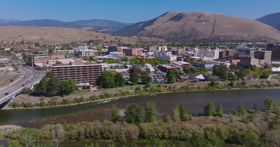 Wide aerial tracking right of Missoula Montana city beside Clark Fork River and hills