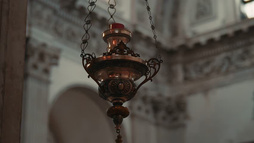 Traditional sanctuary lamp with candle and chains against cathedral columns at Brescia Cathedral, Italy, panning shot