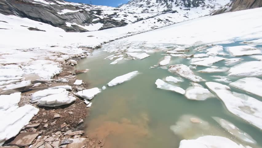 Close-up aerial drone shot flying over a glacial lake filled with melting ice floes.