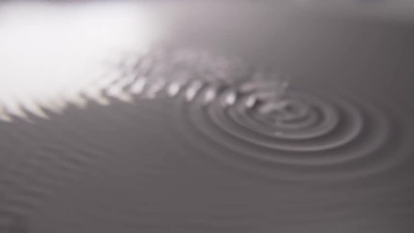 Close-up view of water surface disturbed by sound waves, forming intricate patterns and ripples