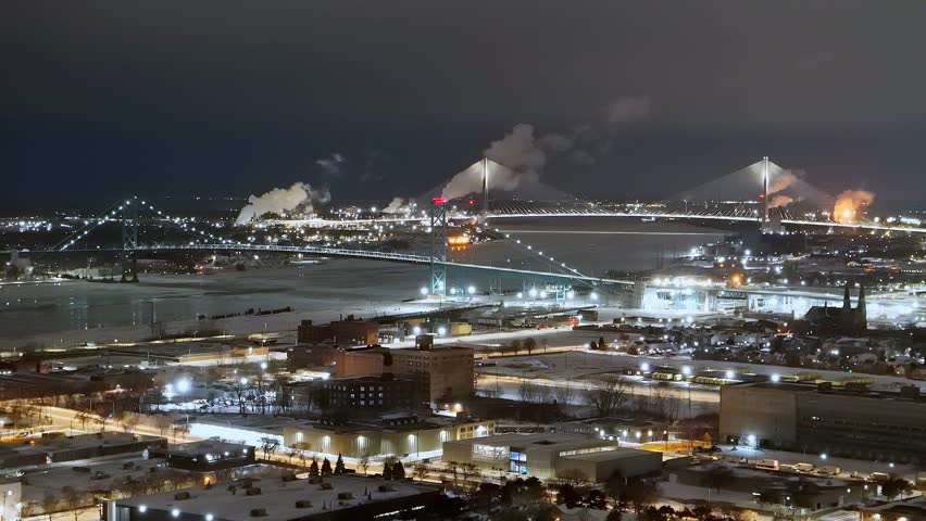 Ambassador Bridge and Gordie Howe International Bridge spanning Detroit River, connecting Detroit and Windsor, Michigan, USA in aerial view on winter night
