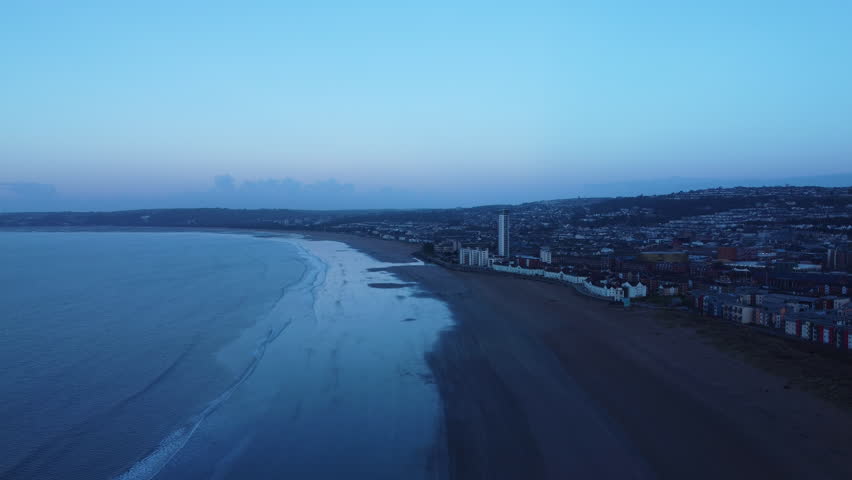 Blue Hour Wide Landscape Aerial of Swansea Bay at Low Tide with Waterfront Buildings and Apartments. 2nd Largest City in Wales, UK.