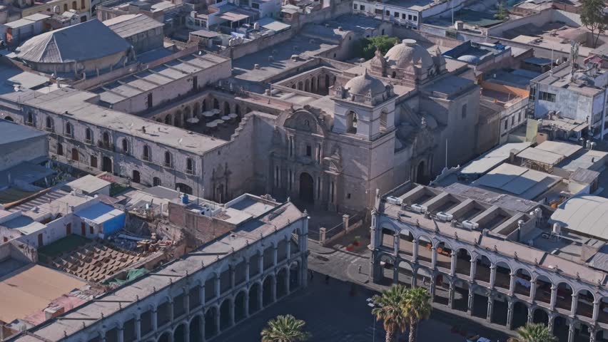 Andean Baroque Church of the Society of Jesus on Plaza de Armas in Arequipa as a drone pulls backward revealing the historic colonial complex.