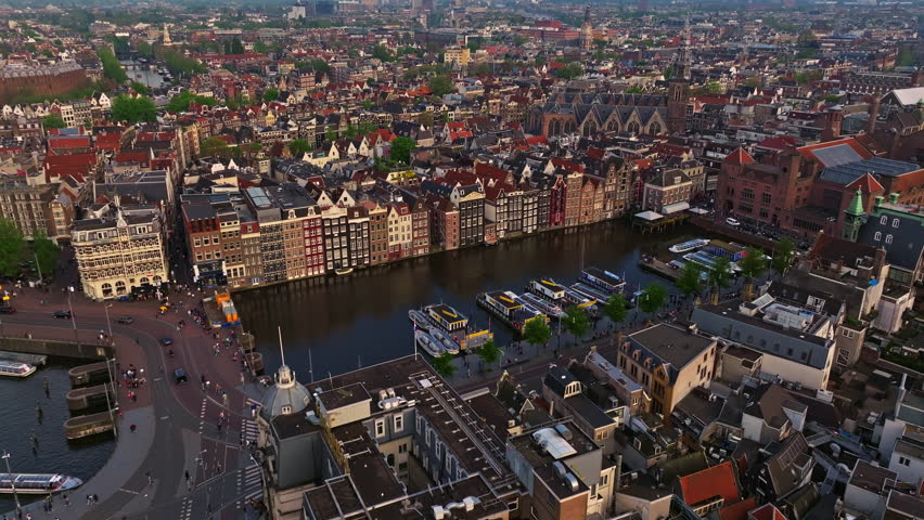 Aerial view of Amsterdam city at sunset, Netherlands. Amsterdam Central Station. Canals with boats in the center city, old centre 