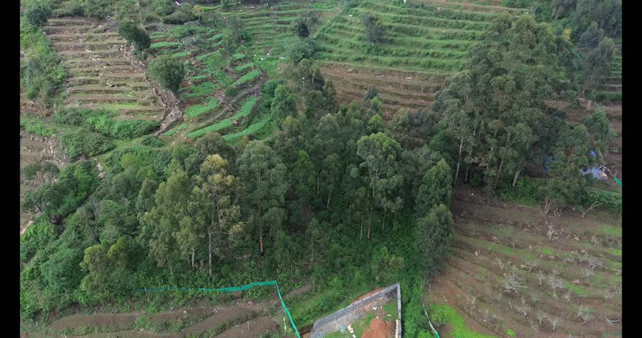 A tranquil mountain valley with layered terrace farms and a narrow road cutting through the hills, representing rural agriculture and connectivity to nearby cities.