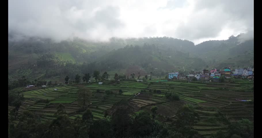 A tranquil mountain valley with layered terrace farms and a narrow road cutting through the hills, representing rural agriculture and connectivity to nearby cities.
