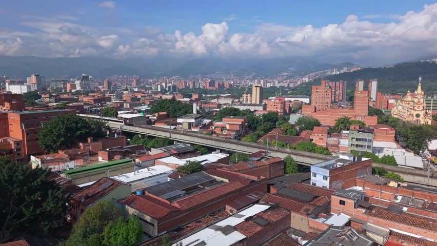Tram in Medellín with city skyline, known for Comuna 13 and Metrocable