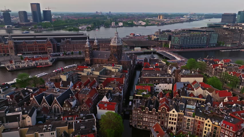 Aerial view of Amsterdam city at sunset, Netherlands. Amsterdam Central Station. Canals with boats in the center city, old centre 