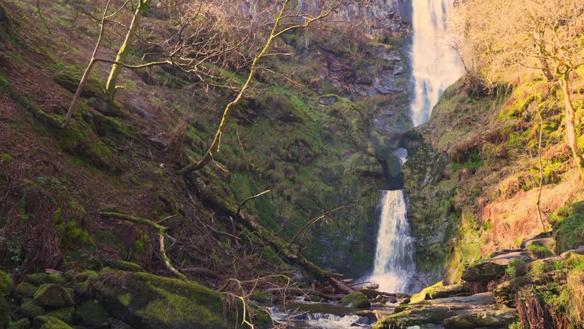View of the lower section of the Pistyll Rhaeadr waterfall in Wales, UK during springtime with harsh sunlight