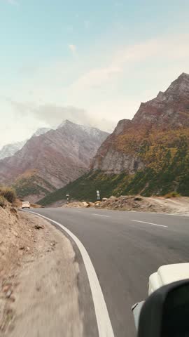 4K POV vertical shot of car driving on asphalt road in mountains during sunset at Lahaul, Himachal Pradesh, India. Travel, adventure and road trip concept. Summer vacation trip in mountains.