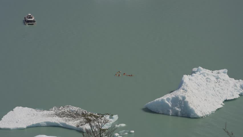 Aerial view of kayakers on a lake near large floating icebergs in nature