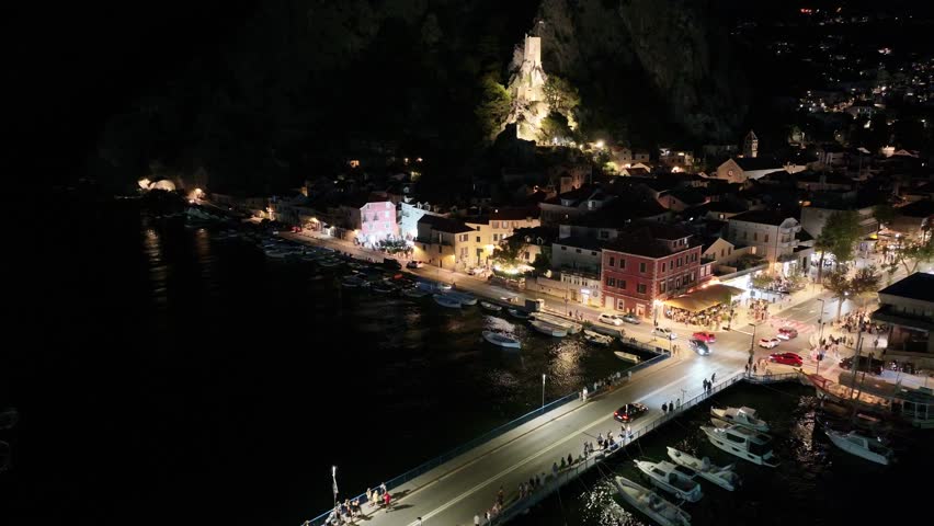 Historic Mirabela fortress glowing above Omis old town during night in Dalmatia, Croatia.