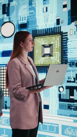 Vertical video Engineering team analyzing semiconductor fabrication with laptop, looking at display. Teamworking PCB factory colleagues oversee microprocessor production with notebook, camera A