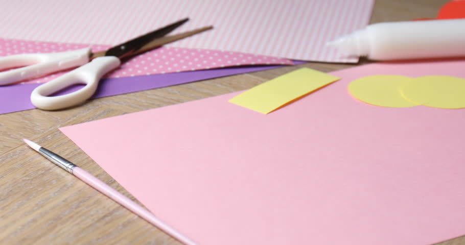 Woman applying glue on piece of paper at wooden table, closeup
