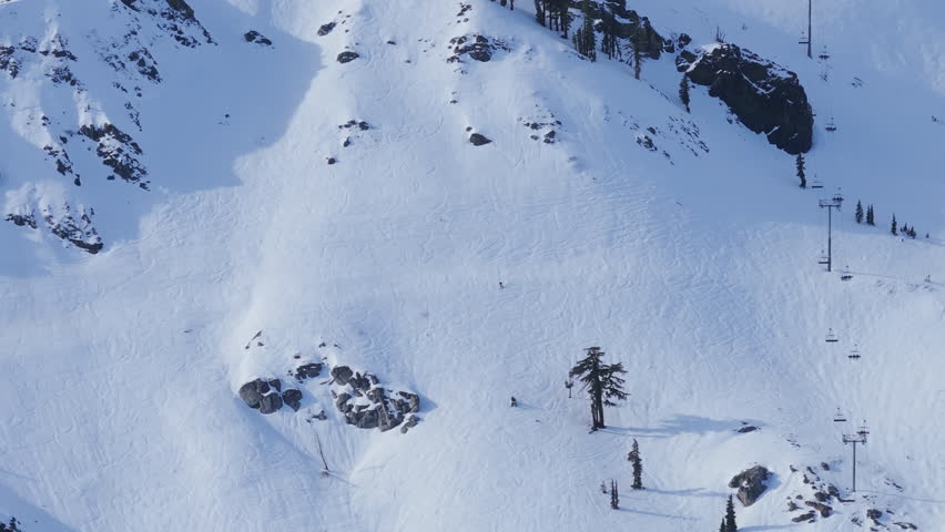 Winter mountain ride with skiers and snowboarders moving down snow covered slopes in Palisades Tahoe, California USA. Natural alpine landscape and dynamic sports action.