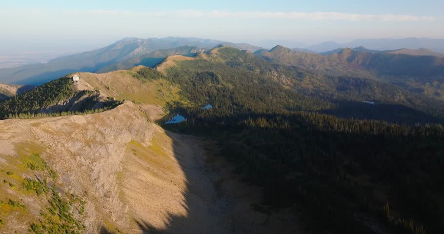 Rocky mountain ridge with forested slopes in Jewel Basin Montana, aerial pullback