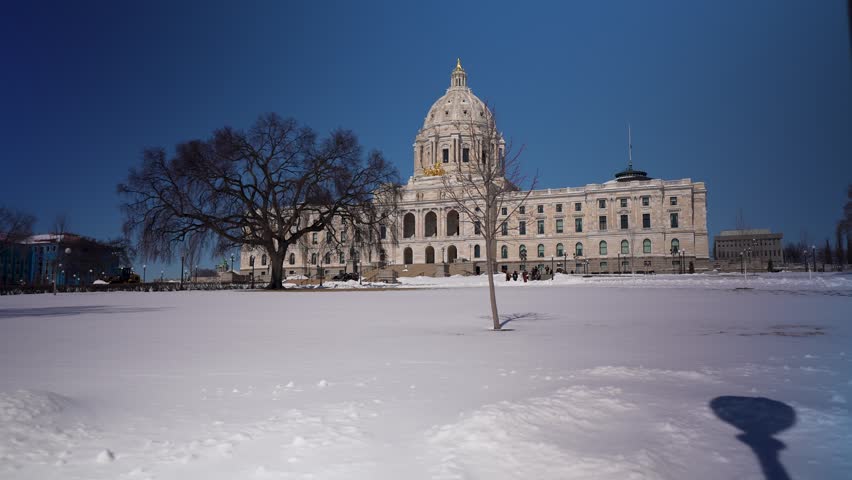 Minnesota state Capitol stands tall in Saint Paul with bright sun shining on the snow-covered landscape during winter.