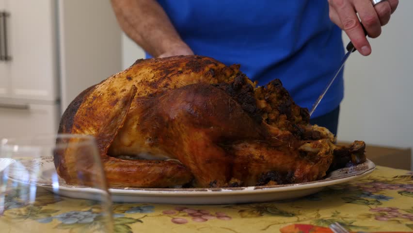 Person carving roasted turkey for holiday meal, delicious cooked poultry ready to be served